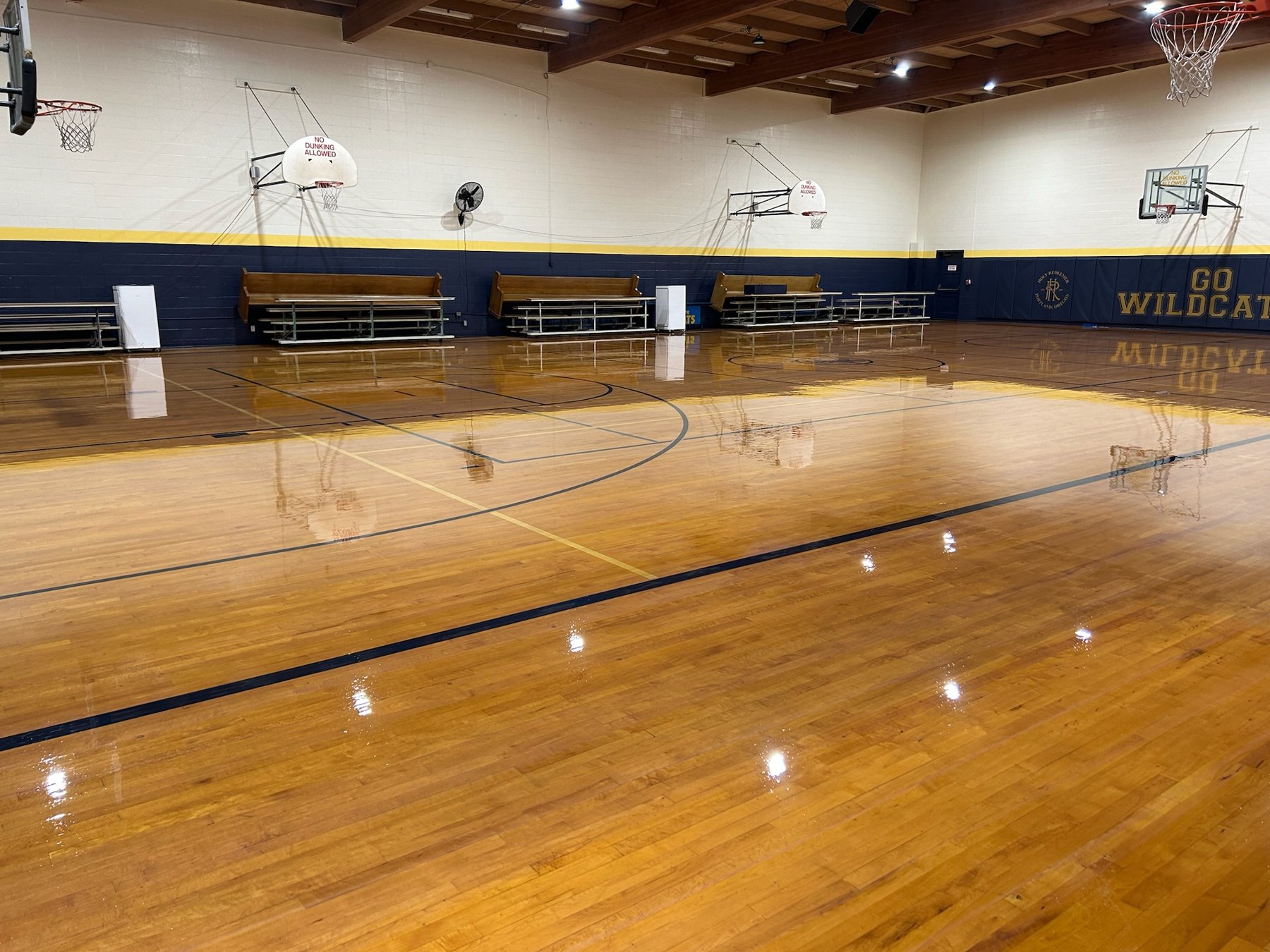 Refinished hardwood gymnasium floor with mirror gloss and crisp game lines